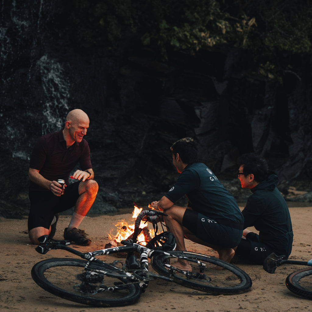 Bikepacking gravel cyclists around camp fire enjoying a gravel cycling beer by GRVL apparel